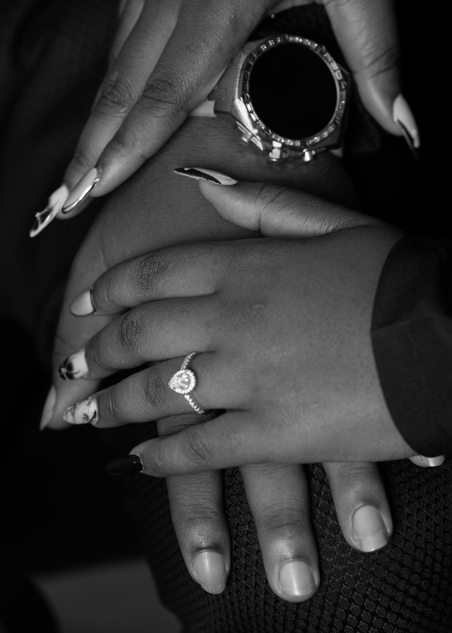 Black and white photo focusing on hands with elegant rings and manicured nails, symbolizing love and commitment.